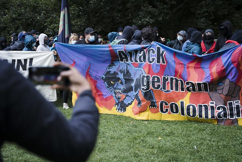 Activists carry a banner that says 'Attack German Colonialism'