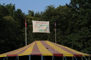 Zirkuszelt mit Fahne auf der Steht 'Geschichte ist machbar - System Change auch!'
