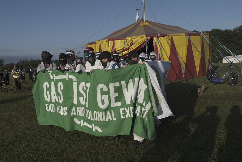 Ein Demoblock mit grünem Fronttranspi auf dem "Gas ist Gewalt" steht. Im Hintergrund ein Zirkuszelt